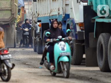 Pengendara sepeda motor melintas di antara truk yang terjebak kemacetan di Jalan Raya Parung Panjang, Bogor, Jawa Barat, Sabtu (9/12/2023). Kemacetan terjadi imbas dari sejumlah sopir truk yang berunjuk rasa terkait jam operasional truk tambang di depan Kecamatan Parung Panjang pada Jumat (8/12) malam. (merdeka.com/Arie Basuki)