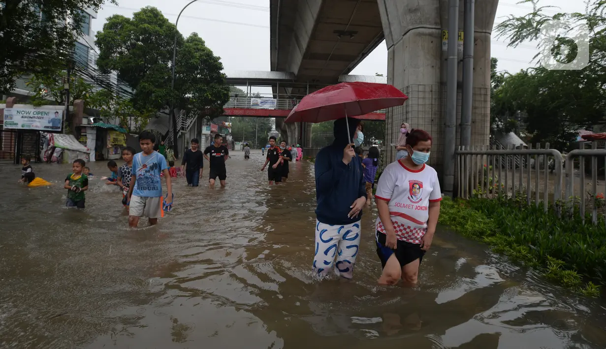Warga berjalan menyusuri banjir yang merendam Jalan Kapten Tendean, Jakarta, Sabtu (20/2/2021). Banjir yang disebabkan curah hujan tinggi memutus akses lalu lintas di Jalan Kapten Tendean. (merdeka.com/Imam Buhori)