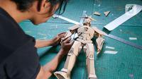 Perajin menyelesaikan pembuatan robot dari kardus di Workshop Bumi Kardus, Depok, Jawa Barat, Jumat (15/7/2022). Kerajinan berbahan baku kardus tersebut dijual dengan harga Rp 400 ribu hingga Rp 60 juta tergantung tingkat kesulitan dan ukuran. (Liputan6.com/Herman Zakharia)
