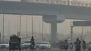 Sejumlah kendaraan melintas di tengah kondisi kabut asap tebal di New Delhi (30/10). Tingkat kabut melonjak selama musim dingin di Delhi, ketika kualitas udara sering melampaui tingkat aman Organisasi Kesehatan Dunia. (AFP Photo/Prakash Singh)