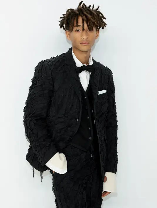 Jaden Smith berpose menghadiri CFDA Fashion Awards di Cipriani South Street di New York pada Senin, 7 November 2022. Mantelnya termasuk kerah ramping dan saku miring di samping. Dia memadukannya dengan rompi beludru dan kemeja putih berkancing yang menampilkan manset dramatis dengan potongan lingkaran kecil. (Dimitrios Kambouris/Getty Images/AFP)