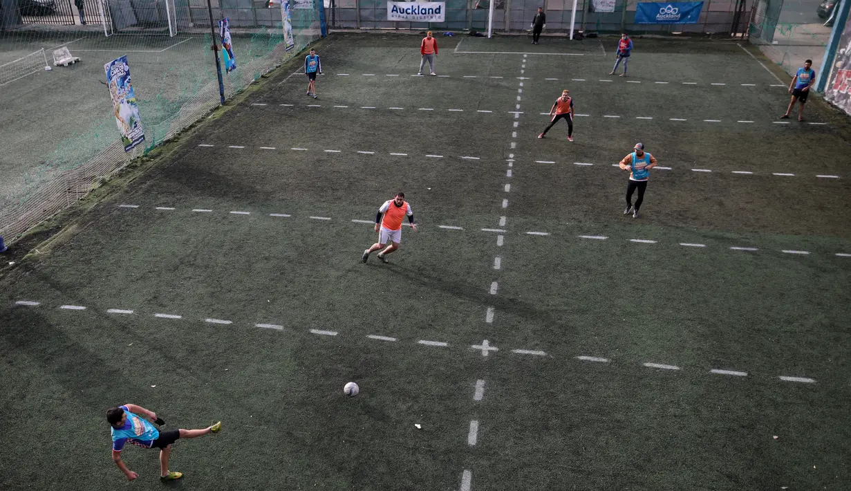 Sejumlah pria bermain sepak bola di klub lokal, Play Futbol 5, di Pergamino, Argentina, 1 Juli 2020. Demi bisa bermain di tengah pandemi Covid-19, klub membagi lapangan menjadi 12 persegi panjang untuk menandai area terbatas untuk setiap pemain, menjaga melakukan kontak fisik. (AP/Natacha Pisarenko)