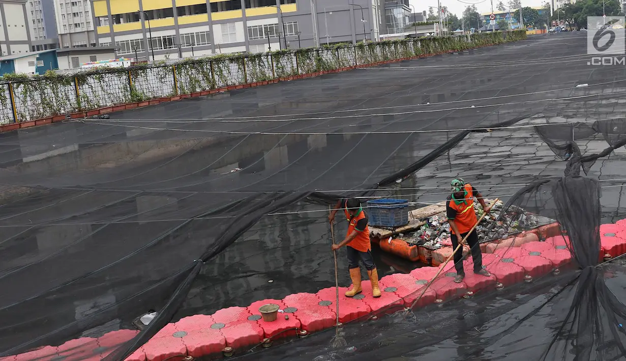 Petugas membersihkan Kali Item yang tertutup kain waring atau jaring di Kemayoran, Jakarta, Minggu (4/11). Sampah plastik, botol mineral, kaleng dan bungkus rokok bertebaran di waring yang membentang di atas Kali Item. (Liputan6.com/Immanuel Antonius)