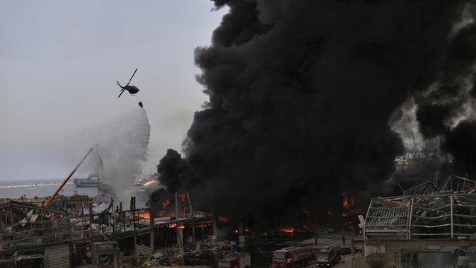 Helikopter tentara menjatuhkan air ke dalam api yang membakar gudang di Pelabuhan Beirut, Lebanon, Kamis (10/9/2020). Kebakaran tersebut menyebabkan kepanikan warga Beirut karena terjadi di lokasi ledakan dahsyat yang menewaskan 200 orang pada bulan lalu. (AP Photo/Hassan Ammar)