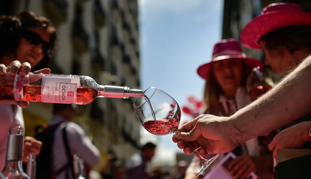 Seorang wanita menuangkan anggur mawar Spanyol untuk mempromosikan minuman tersebut di Pamplona, Spanyol, Sabtu (19/5). Acara ini dilakukan pada musim semi yang cerah. (AP Photo/Alvaro Barrientos)