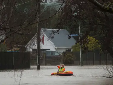 Warga menggunakan perahu kecil melintasi banjir di Christchurch, Selandia Baru, Sabtu, (22/7). Dewan Kota Christchurch mengatakan keadaan darurat setelah Sungai Heathcote meluap akibat cuaca yan buruk. (AP Photo / Mark Baker)