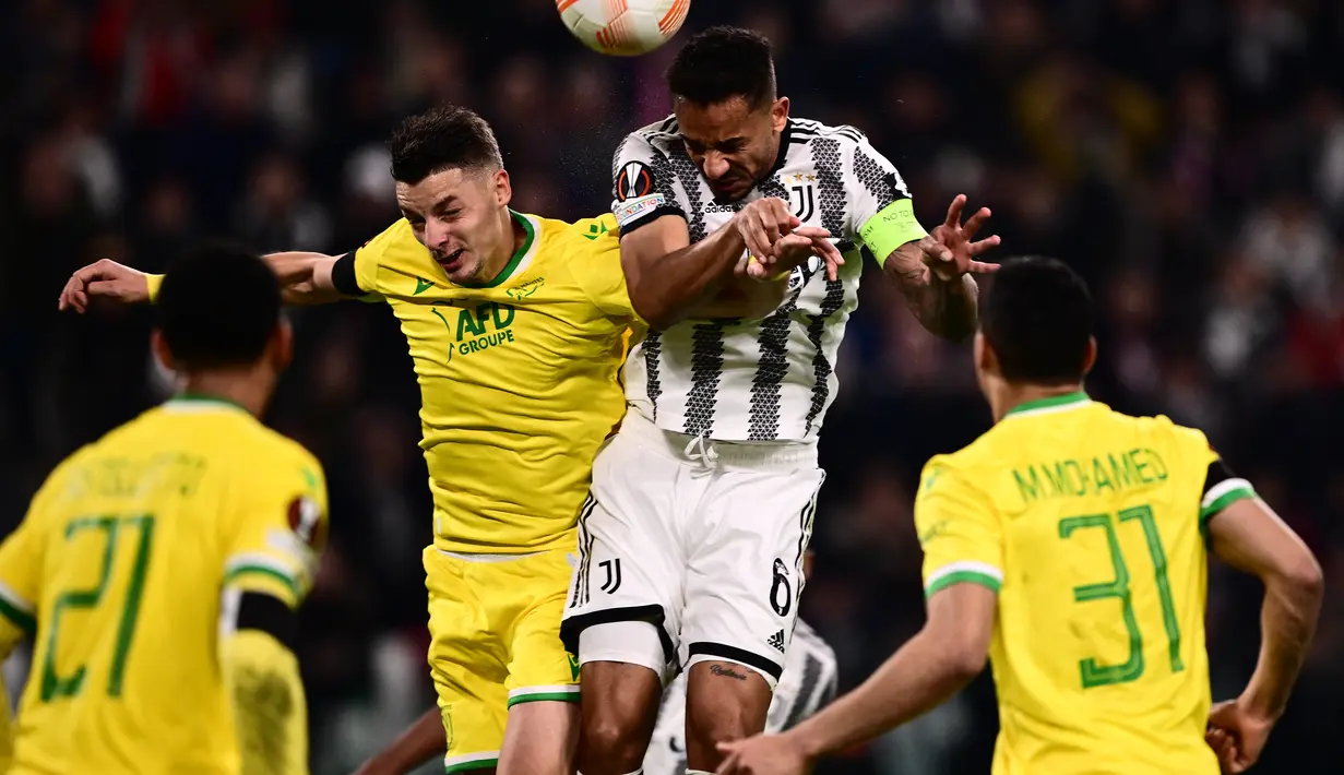 Gelandang Nantes Andrei Girotto (Kiri) dan bek Juventus Danilo melakukan sundulan dalam duel leg pertama play-off babak gugur Liga Europa 2022/2023 di Allianz Stadium, Jumat (17/2/2023) dini hari WIB. Juventus ditahan imbang Nantes dengan skor 1-1. (Photo by Marco BERTORELLO / AFP)