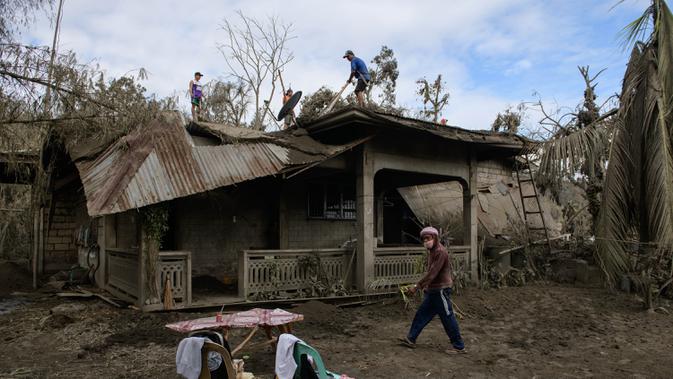 Sejumlah warga membersihkan abu vulkanik dari atap rumah mereka setelah letusan Gunung Taal di Desa Buso-Buso, Laurel, Provinsi Batangas, Filipina, Kamis (17/1/2020). Pihak berwenang Filipina memperingatkan bahwa potensi Gunung Taal untuk kembali meletus masih tinggi. (Ed JONES/AFP)