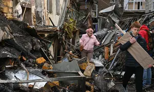 Warga setempat berjalan di halaman sebuah lingkungan perumahan yang rusak parah setelah serangan Rusia di Odesa, Ukraina, Jumat 24 April 2026. Gelombang serangan udara Rusia yang menggunakan kombinasi pesawat nirawak (drone) dan rudal kembali menghantam jantung permukiman warga Ukraina. (AP Photo/Michael Shtekel)