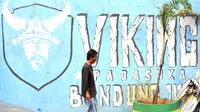 Seorang warga melintas dekat mural Viking di Bandung. (Bola.com/Nicklas Hanoatubun)