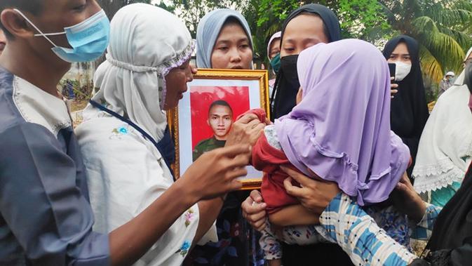 Istri prajurit TNI Gugur di Poso mencium foto suaminya itu saat pemakaman di Pekanbaru. (Liputan6.com/M Syukur)