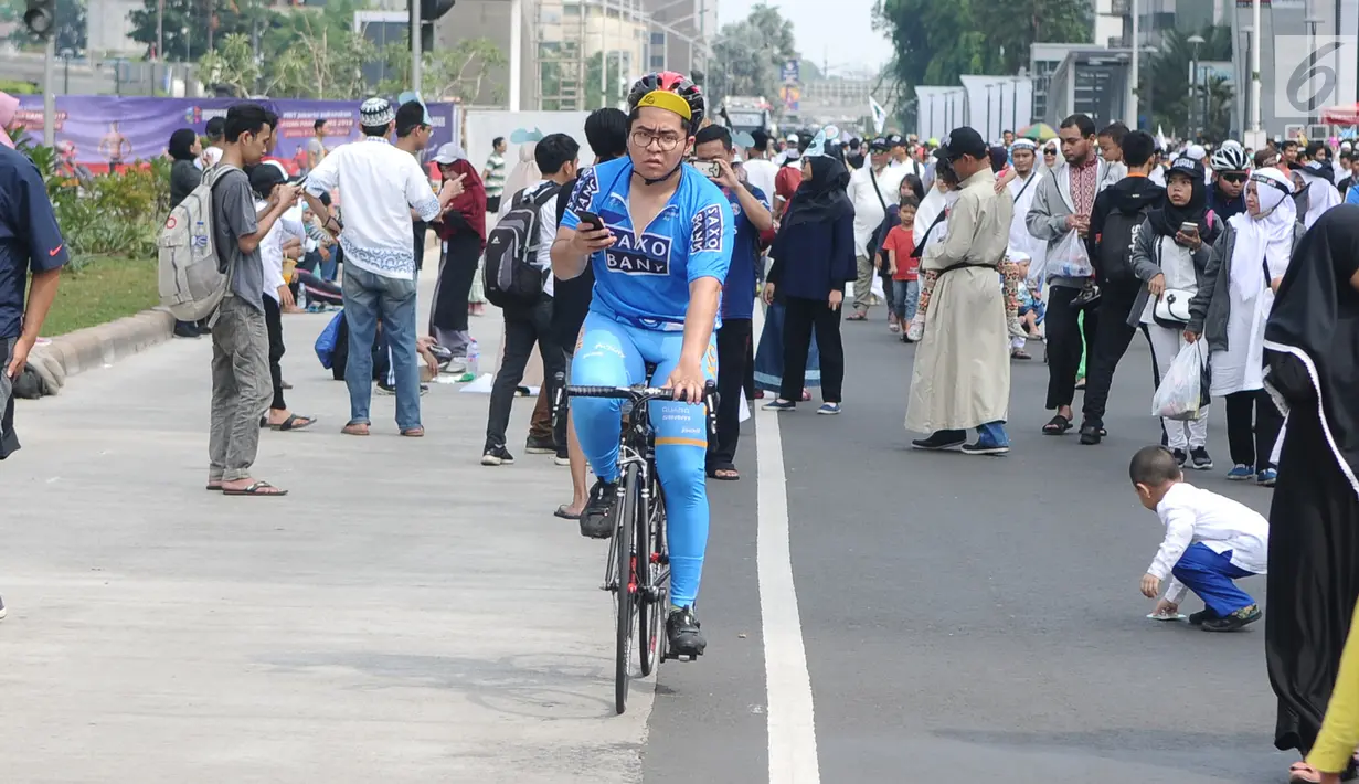 Seorang warga bersepeda di antara peserta Reuni 212 saat Car Free Day (CFD) di kawasan Jakarta, Minggu (2/12). Warga tetap memadati area Car Free Day  dari Bundaran HI-Sudirman meskipun ada aksi Reuni 212. (Liputan6.com/Angga Yuniar)