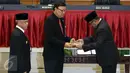 Gubernur Banten Rano Karno (kanan) memberikan surat Pelaksana Tugas Gubernur kepada Mendagri Tjahjo Kumolo (tengah) saat prosesi peresmian Plt Gubernur dan Serah Terima Nota Pengantar Tugas di Kemendagri, Jakarta, Rabu (26/10). (Liputan6.com/Johan Tallo)