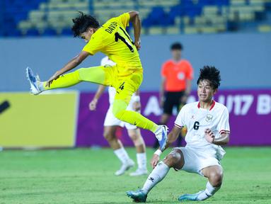 Pemain Timnas Malaysia, Dawud lmran Bin Rozlin, menendang bola saat berebut bola dengan Timnas Indonesia U-17, Girly Andrade Guevara, pada laga kedua Grup A Piala AFF U-17 2026 di Stadion Gelora Joko Samudro, Gresik, Jawa Timur, Kamis (16/4/2026) malam. (Bola.com/M Iqbal Ichsan)