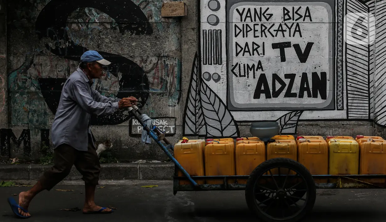 Penjual air melintasi di depan mural di kawasan Jakarta Pusat. Selasa (24/8/2021). Menjamurnya mural dan grafiti penuh muatan kritikan merupakan suara para seniman untuk berekspresi di tengah pandemi. (Liputan6.com/Johan Tallo)