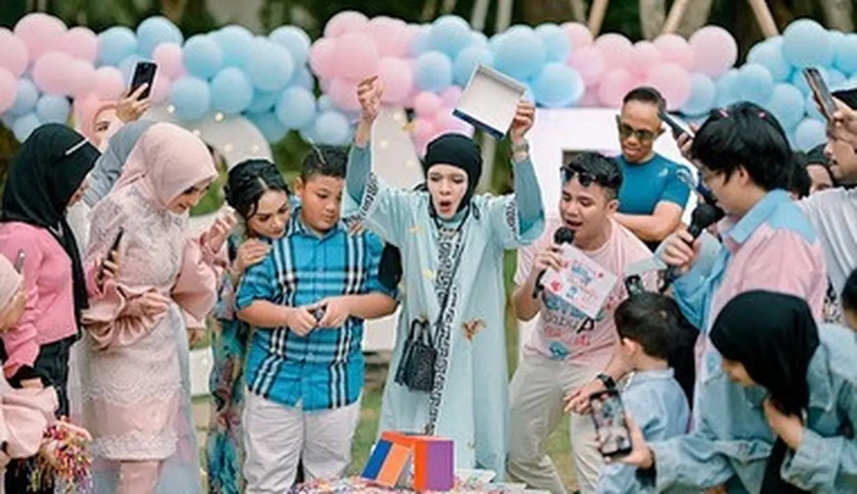 Selain balon-balon biru muda dan merah muda, semua keluarga yang hadir dalam acara tersebut juga mengenakan pakaian serupa. Biru muda menebak anak Aurel laki-laki dan merah muda menebak anak kedua Aurel perempuan. Waktunya tiba, akhirnya diketahui calon adik baby Ameena berjenis kelamin perempuan. [Instagram/genifaruk]