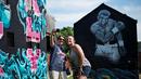 Warga berfoto di depan mural Muhammad Ali di Louisville, Kentucky, AS, (10/6/2016). (AFP/Brendan Smialowski)