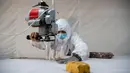 Pekerja memotong bahan untuk digunakan membuat pakaian antivirus di pabrik garmen Zhejiang Ugly Duck Industry, di Wenzhou, 28 Februari 2020. Wabah virus corona di China membuat produsen pakaian itu mulai memproduksi baju hazmat yang banyak diburu orang untuk melindungi dirinya. (NOEL CELIS/AFP)