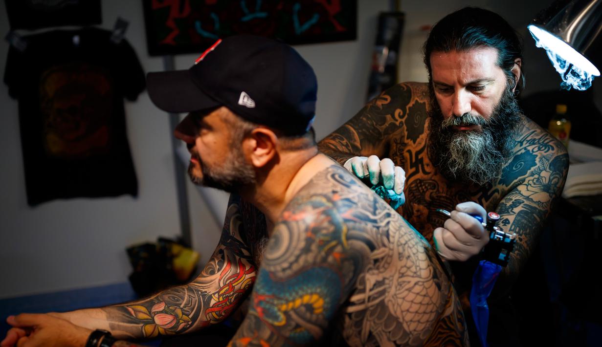 Seorang seniman mentato badan pengunjung dalam acara edisi keempat Montreux Tattoo Convention di Montreux, Swiss  (22/9). Montreux Tattoo Convention berlangsung selama tiga hari. (Valentin Flauraud/Keystone via AP)