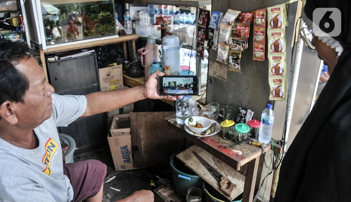 Pedagang menyaksikan tayangan pada gawainya yang menyiarkan langsung rekonstruksi pembunuhan Brigadir Nofriansyah Yosua Hutabarat alias Brigadir J melalui smartphone di Pasar Senen, Jakarta Pusat, Selasa (30/8/2022). Rekonstruksi ulang pembunuhan Brigadir J yang dihadiri oleh lima tersangka, yakni Ferdy Sambo, Bharada Richard Eliezer (Bharada E), Bripka Ricky Rizal, Kuat Ma'ruf, dan Putri Candrawathi itu menjadi perhatian warga dari berbagai kalangan untuk menyaksikan secara langsung meski hanya melalui siaran televisi atau gawai. (merdeka.com/Iqbal S. Nugroho)