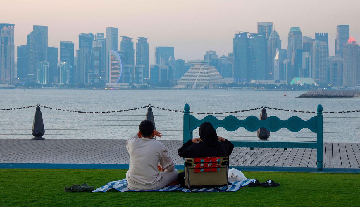 Tradisi ini menciptakan suasana khas yang meriah dan memperkuat kebersamaan selama bulan suci Ramadan. Tampak dalam foto, orang-orang menyantap hidangan buka puasa (iftar) di Pelabuhan Doha Lama, Qatar selama bulan suci Ramadan 1447 Hijriah pada Kamis 24 Februari 2026. (Karim JAAFAR/AFP)