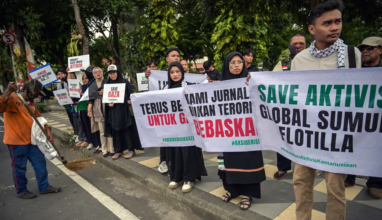 Seorang pekerja menyapu jalan saat para aktivis mengadakan unjuk rasa menentang pencegatan kapal-kapal yang berpartisipasi dalam armada Global Sumud Flotilla (GSF), sebuah misi bantuan kemanusiaan ke Gaza melalui jalur laut, di Surabaya, Jawa Timur pada Kamis 21 Mei 2026. (JUNI KRISWANTO/AFP)