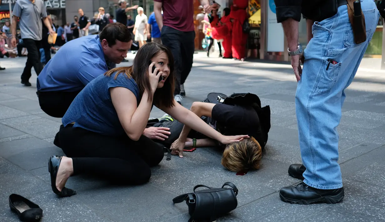 Sejumlah orang menghampiri korban terluka setelah dihantam sebuah mobil trotoar Times Square, New York, Kamis (18/5). Saksi mata mengatakan pengemudi mobil tersebut masuk ke jalur pejalan kaki ketika jalan sekitarnya sedang macet. (Jewel SAMAD/AFP)