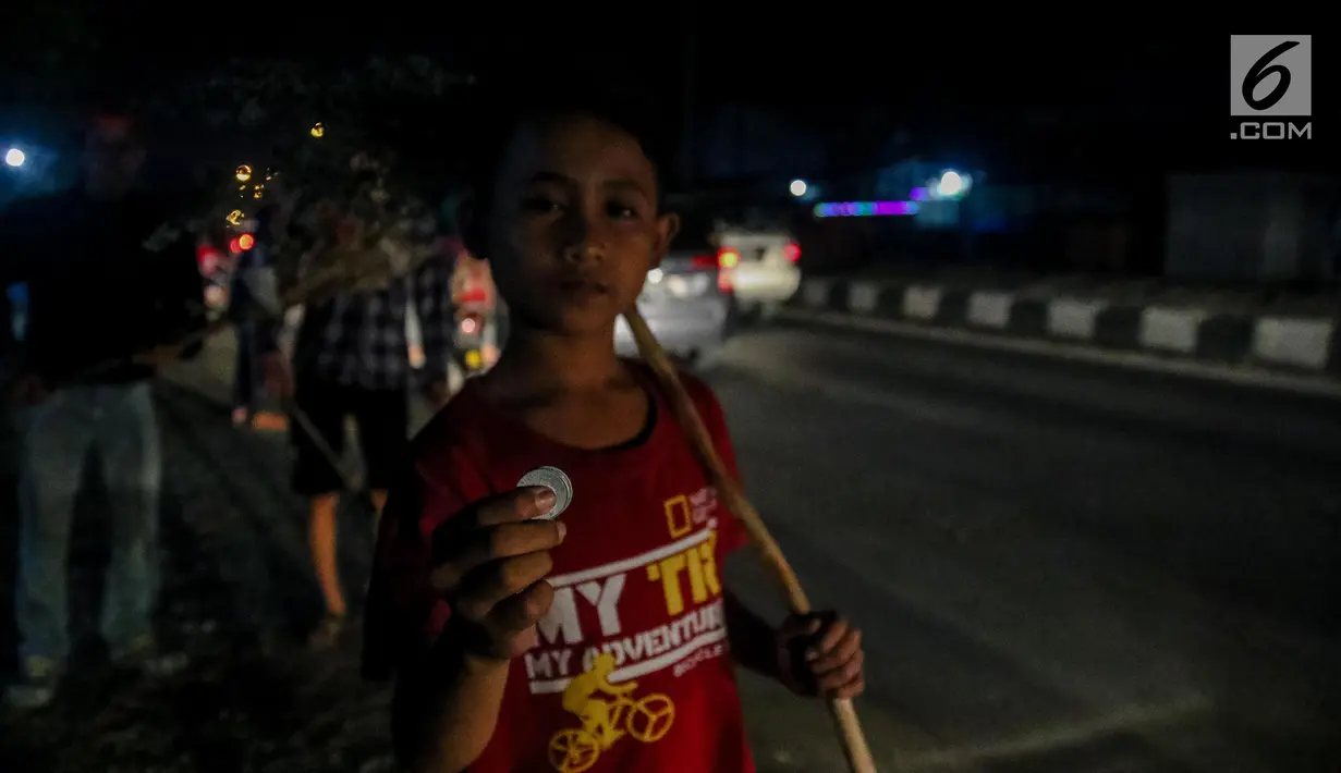 Seorang anak menunjukan uang koin hasil dari menyapu di Jembatan Sewo, Kabupaten Indramayu, Jawa Barat, Minggu (2/7). Aktivitas sapu uang ini biasa dilakukan warga sekitar untuk mendapat rezeki dari pemudik. (Liputan6.com/Faizal Fanani)