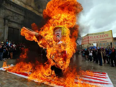 Para pengunjuk rasa membakar patung karakter Presiden AS Donald Trump saat melakukan aksi protes pada peringatan Hari Buruh di Bogota, Kolombia (1/5). Warga Kolombia merayakan Hari Buruh dengan membakan patung Donald Trump. (AP/Fernando Vergara)