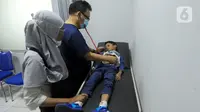 Dokter Desman Siahaan melakukan pemeriksaan pasien anak yang menderita infeksi saluran pernafasan akut (ISPA) di Klinik BPJS Prima Husada, Depok, Jawa Barat, Rabu (16/8/2023). Sejumlah klinik kesahatan dan rumah sakit di kawasan Jabodetabek merasakan adanya kenaikan kasus ISPA di tengah buruknya udara Jabodetabek. (merdeka.com/Arie Basuki)