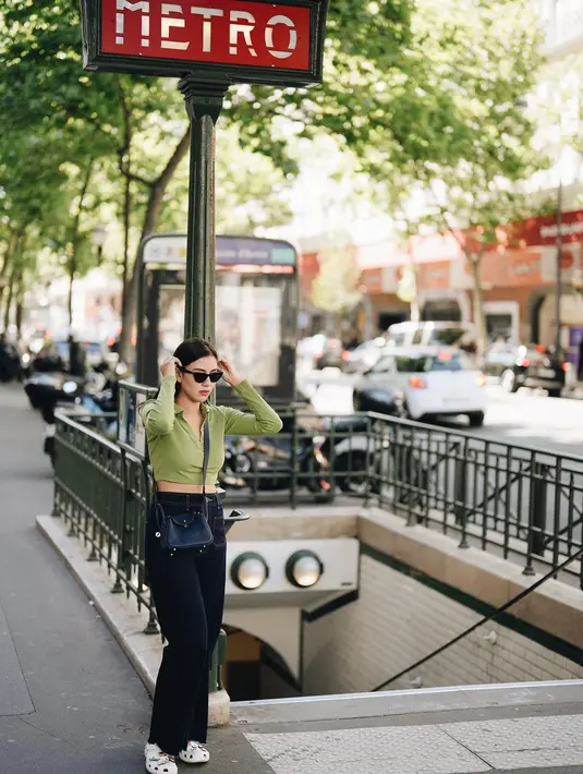 Gaya yang tak kalah menawan dari Syahnaz Sadiqah saat berlibur ke Paris. Ia tampil chic dengan cropped top lengan panjang berwarna hijau, dipadu celana jeans, sling bag hitam, alas kaki putih, dan sunglasses. [Foto: Instagram/syahnazs]