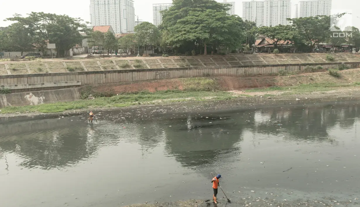 Dua pekerja membersihkan sampah yang mengotori aliran Kanal Banjir Timur (KBT), Jakarta, Sabtu (15/9). Banyaknya limbah rumah tangga dan limbah industri menyebabkan kanal pengendali banjir tersebut selalu tercemari sampah. (Liputan6.com/Immanuel Antonius)