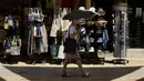 Seorang perempuan berjalan keluar dari sebuah toko suvenir sambil melindungi dirinya dari sinar matahari dengan payung pada hari yang panas di pusat ibu kota Nicosia, Siprus, Selasa (4/6/2024). (AP Photo/Petros Karadjias)
