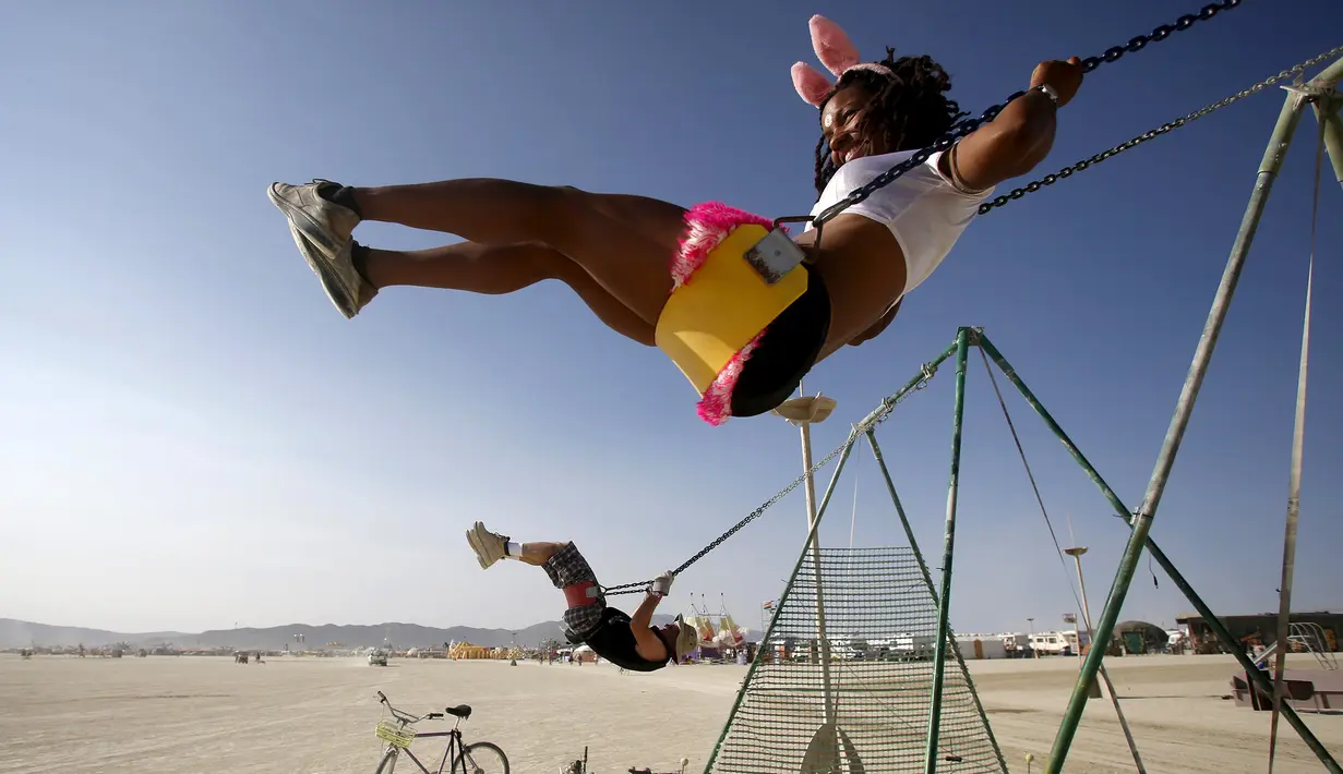 Pengunjung bermain ayunan dalam festival musik dan seni Burning Man 2015 di Gurun Black Rock, Nevada, (1/9/2015). Festival ini mengangkat tema "Carnival of Mirrors." (REUTERS/Jim Urquharther)