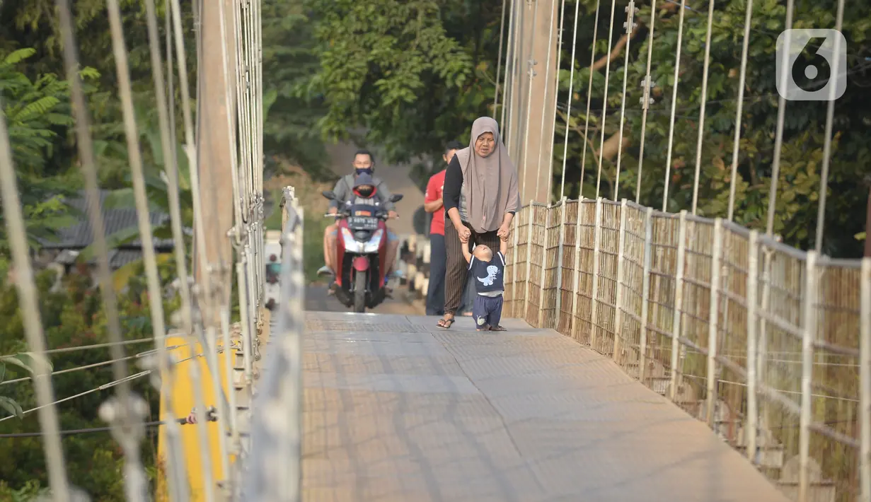 Warga melintasi jembatan gantung di Kelurahan Curug, Bojongsari, Kota Depok, Jawa Barat, Senin (24/8/2020). Setiap sore, warga sekitar bermain di jembatan tersebut sambil menikmati matahari tenggelam. (merdeka.com/Dwi Narwoko)