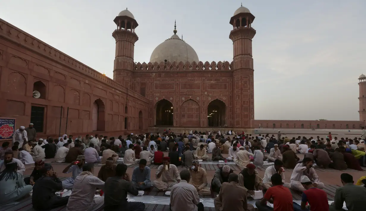 Orang-orang berbuka puasa selama bulan suci Ramadhan di masjid bersejarah Badshahi, di Lahore, Pakistan (3/4/2022). Ramadhan ditandai dengan puasa setiap hari dari fajar hingga matahari terbenam. (AP Photo/K.M. Chaudary)