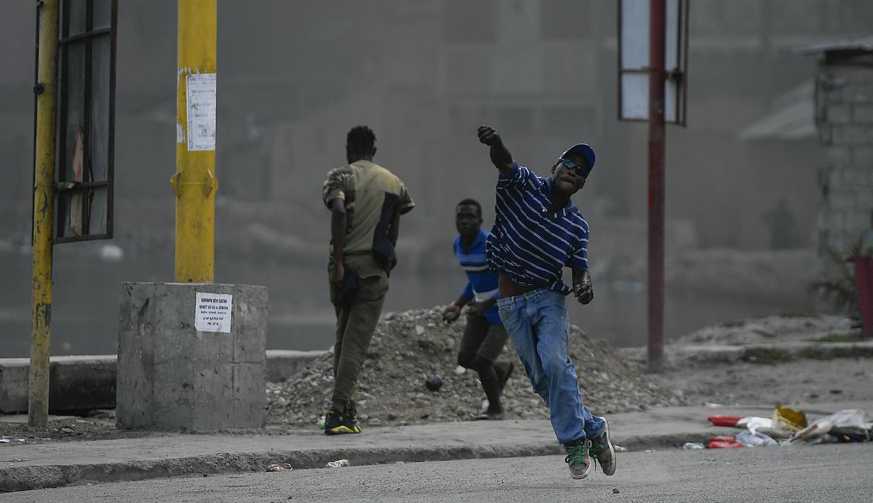 Demonstran melemparkan batu saat menuntut keadilan atas pembunuhan Presiden Haiti Jovenel Moise di Cap-Haitien, Haiti, Kamis (22/7/2021). Demonstrasi menuntut keadilan atas pembunuhan Presiden Haiti Jovenel Moise terus berlanjut dan menimbulkan kerusuhan. (AP Photo/Matias Delacroix)