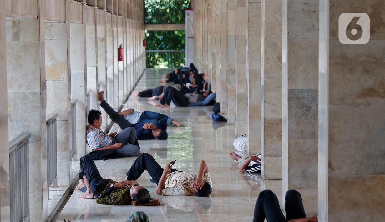 Sejumlah umat muslim yang tengah berpuasa beristirahat usai melaksaanakan shalat Jumat di Istiqlal, Jakarta, Jumat (24/3/2023). (Liputan6.com/Angga Yuniar)