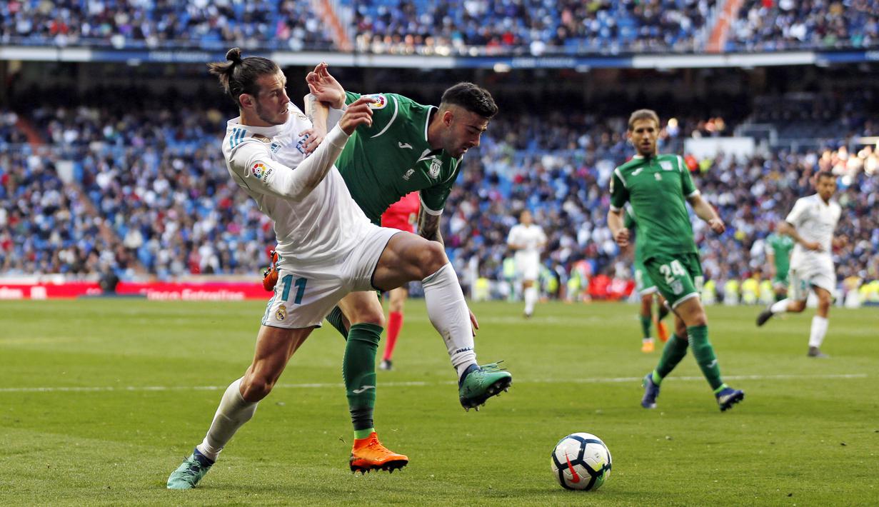 Striker Real Madrid, Gareth Bale, berebut bola dengan pemain Leganes, Diego Rico, pada laga La Liga di Santiago Bernabeu, Sabtu (28/4/2018). Real Madrid menang 2-1 atas Leganes. (AP/Francisco Seco)