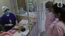 Perawat saat menjelaskan cara memandikan bayi kepada seorang ibu di RSIA Tambak, Jakarta, Kamis (18/02/2021). Melatih para ibu baru untuk memandikan bayi pertama tersebut dilakukan dengan menerapkan protokol kesehatan ketat. (Liputan6.com/Herman Zakharia)