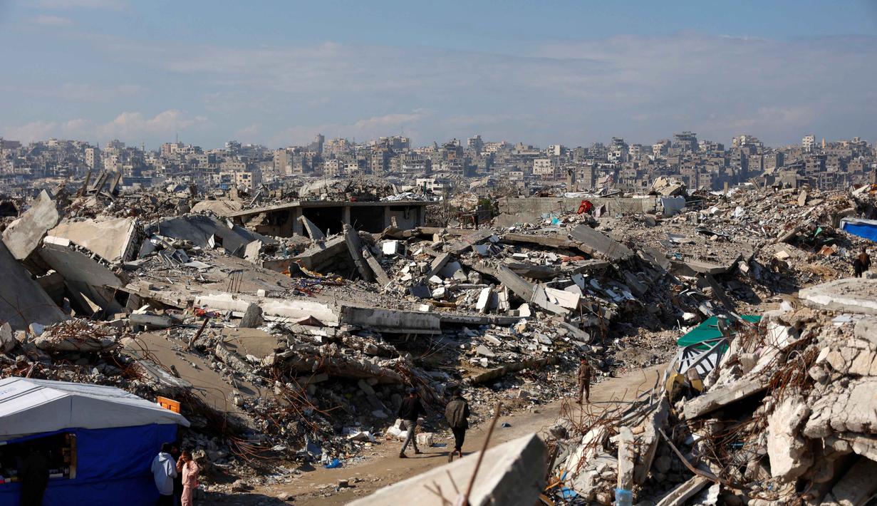 Dewan ini bertugas mendukung administrasi, rekonstruksi, hingga pemulihan ekonomi Jalur Gaza sesuai 20 poin rencana perdamaian Trump untuk mengakhiri perang yang oleh banyak pihak disebut sebagai genosida Israel terhadap warga Palestina. Tampak dalam foto, para pengungsi Palestina hidup di tengah reruntuhan rumah dan bangunan yang hancur akibat serangan militer Israel selama lebih dari dua tahun di wilayah Gaza, di kamp pengungsi Jabalia, di bagian utara Jalur Gaza pada Sabtu 17 Januari 2026. (Omar AL-QATTAA/AFP)