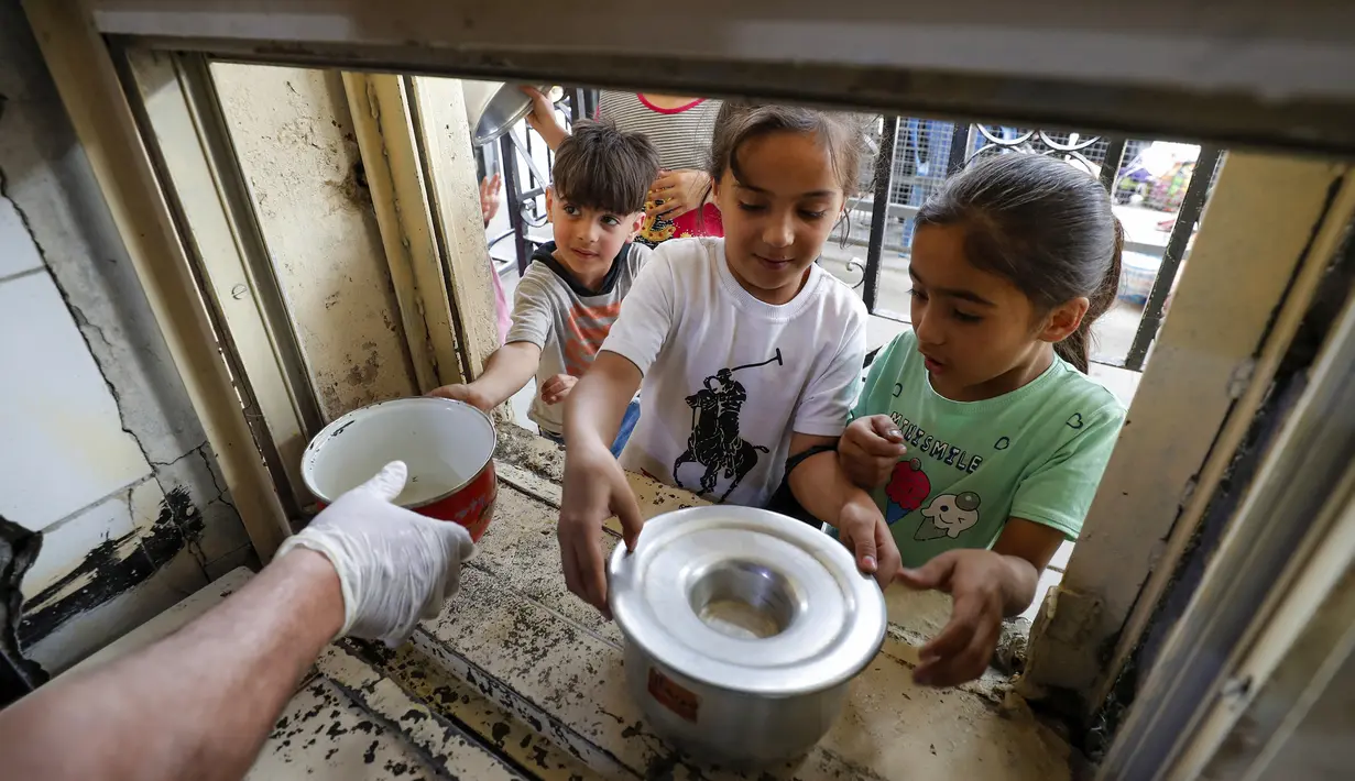 Anak-anak yang membutuhkan antre untuk menerima makanan berbuka puasa dari juru masak di dapur Masjid Muslim Sunni Abdel Kader al-Kilani, Baghdad, Irak, 19 April 2021. Kegiatan ini berlangsung selama bulan suci Ramadhan. (AHMAD AL-RUBAYE/AFP)