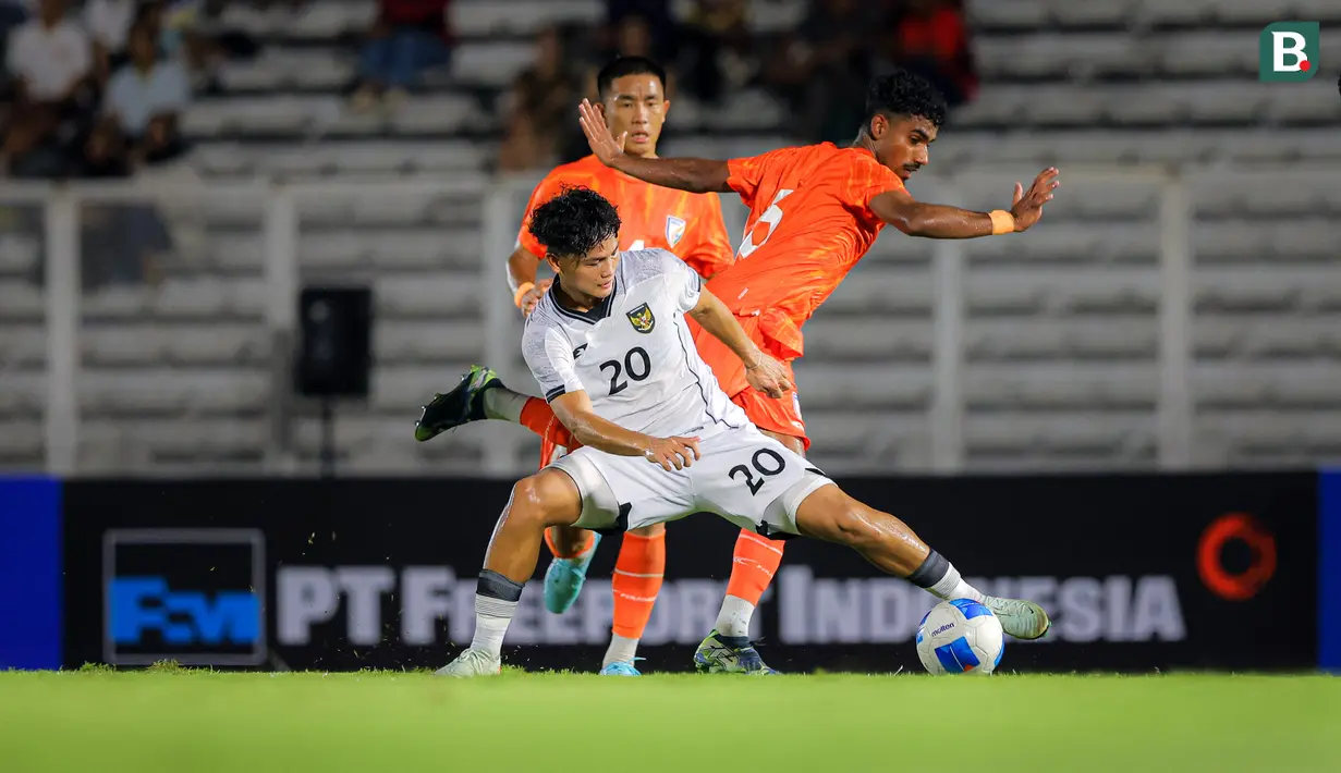 Pemain Timnas Indonesia U-22, Hokyy Caraka (kiri) berebut bola dangen pemain India dalam laga uji coba melawan di Stadion Madya, Senayan, Jakarta, Minggu (13/10/2025). (Bola.com/Bagaskara Lazuardi)