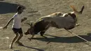 Seekor banteng terjatuh saat berusaha mengejar seorang peserta saat festival Toro de Cuerda di Grazalema, Spanyol, (20/7/2015). Tiga banteng dilepas di jalanan kota dalam festival tahunan tersebut. (REUTERS/Jon Nazca)