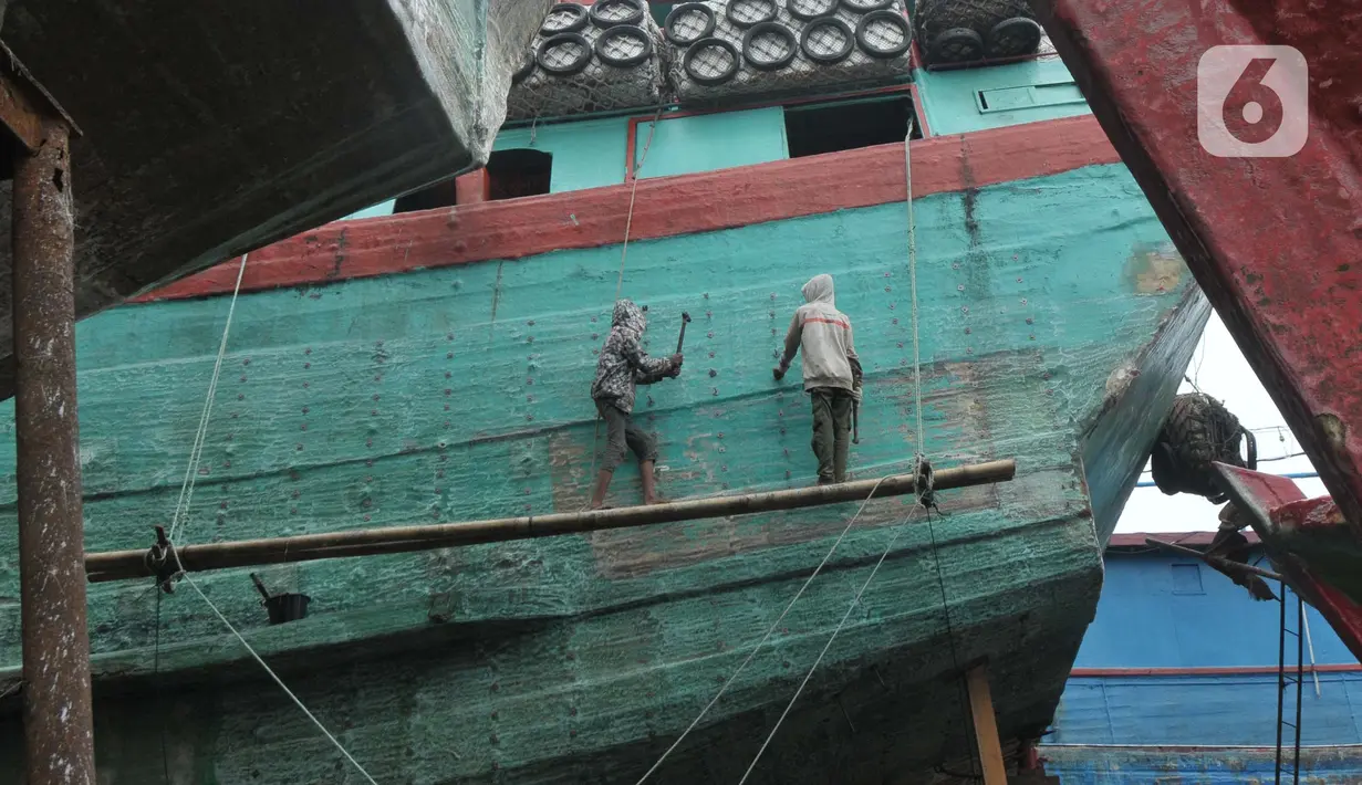 Pekerja menyelesaikan perbaikan kapal nelayan di Galangan Kapal Muara Angke, Jakarta Utara, Kamis (23/5/2024). (merdeka.com/Imam Buhori)