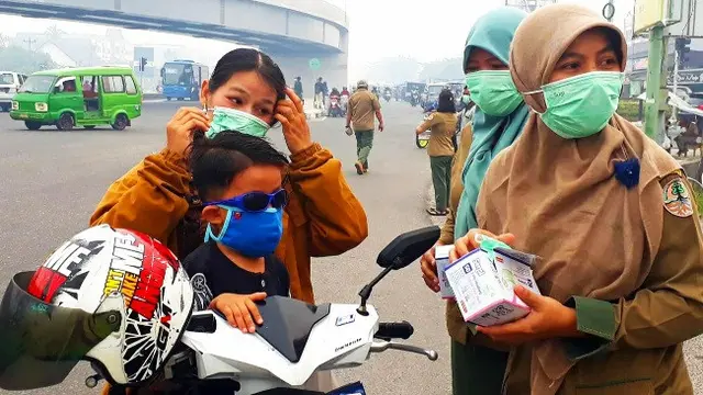 Pegawai BBKSDA Riau membagikan masker kepada warga Pekanbaru agar tidak menghirup kabut asap.
