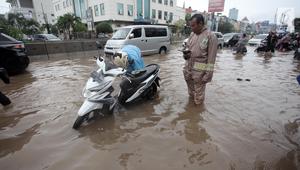 Seorang pengendara memperbaiki motornya yang mogok saat melintasi banjir di Jalan Boulevard Barat Raya, Kelapa Gading, Jakarta, Kamis (15/2). Hujan lebat yang mengguyur Jakarta mengakibatkan sejumlah wilayah terendam banjir. (Liputan6.com/Arya Manggala)