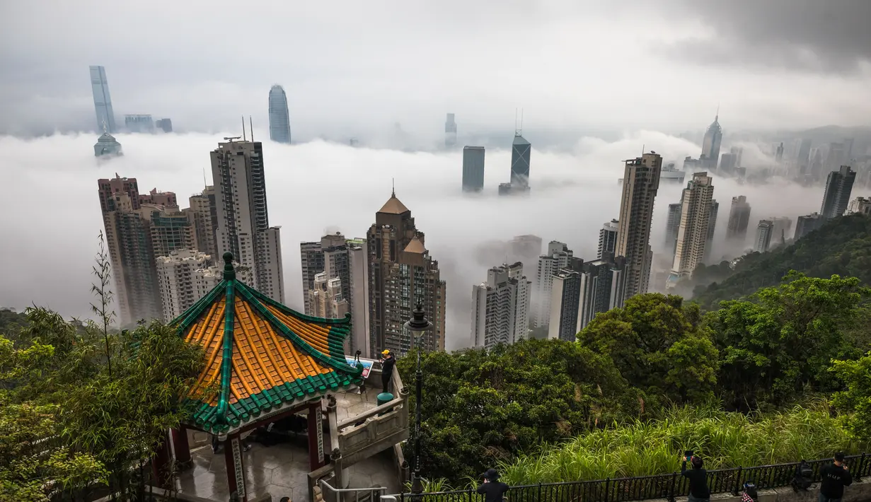 Orang-orang berkumpul di sudut pandang Peak untuk menyaksikan kabut di atas Hong Kong, Selasa (22/3/2022). Kabut tebal menyelimuti Hong Kong pada musim semi ketika wilayah tersebut dipengaruhi oleh udara dingin dan hangat bergantian. (AFP/Dale De La Rey)