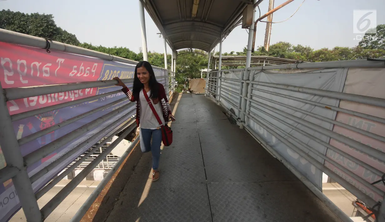 Pejalan kaki sebelum melewati lubang di atas JPO di Halte Bus Transjakarta di Jembatan Gantung, Cengkareng, Jakarta, Jumat (27/7). JPO yang rusak akibat tertabrak truk sejak setahun lalu hingga kini belum diperbaiki.  (Liputan6.com/Arya Manggala)