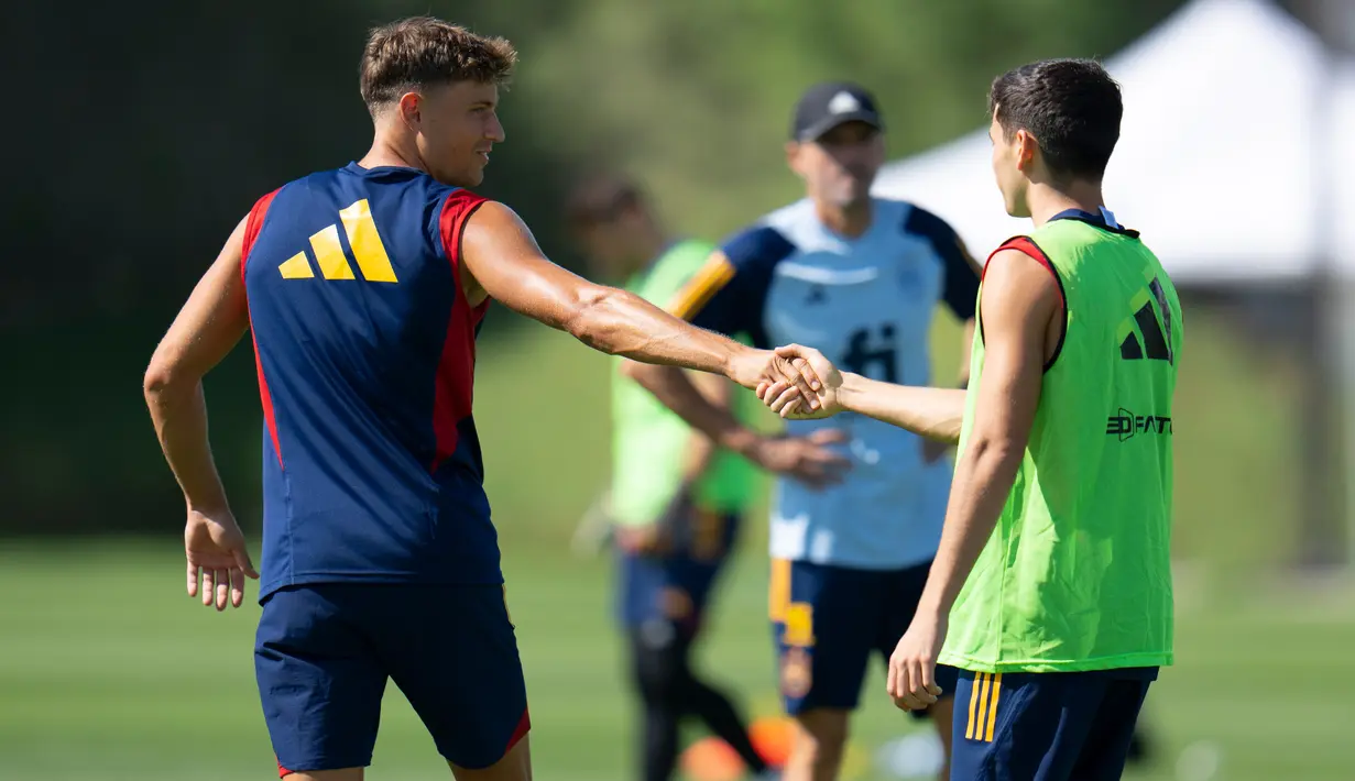Pemain Spanyol Marcos Llorente (kiri) berjabat tangan dengan Pedri saat sesi latihan di Universitas Qatar, Doha, Qatar, Selasa (29/11/2022). Spanyol akan melawan Jepang dalam pertandingan Grup E Piala Dunia 2022 pada 1 Desember mendatang. (AP Photo/Julio Cortez)